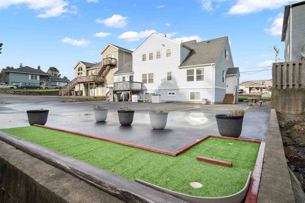 An outdoor mini golf area surrounded by planters and buildings, exuding a playful vibe with space for families and kids to enjoy friendly competition and relaxation.