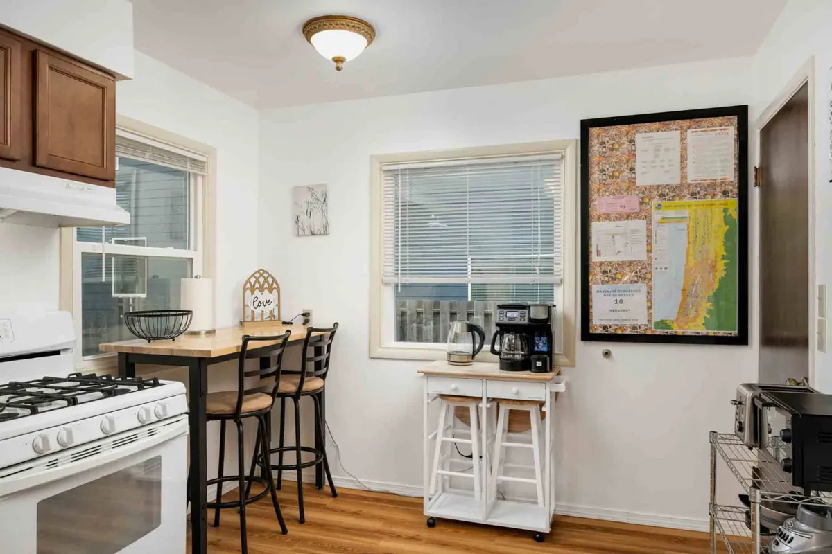 A cozy kitchen scene featuring a central island with bar stools, a dedicated coffee station, tastefully placed wall art, and a relaxed, welcoming mood. The image suggests casual breakfasts, morning routines, and intimate gatherings, with easy access to everything needed for preparing and enjoying meals.