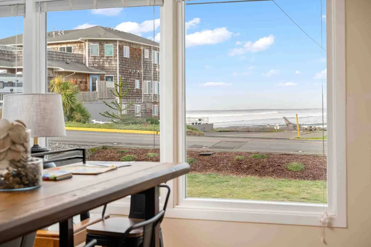 A serene dining area with a large window offering expansive ocean views, a decorative lamp casting warm light, and a table set for quiet reflection or casual meals. The scene exudes calm and invites moments of pause to appreciate the coastal landscape from indoors.