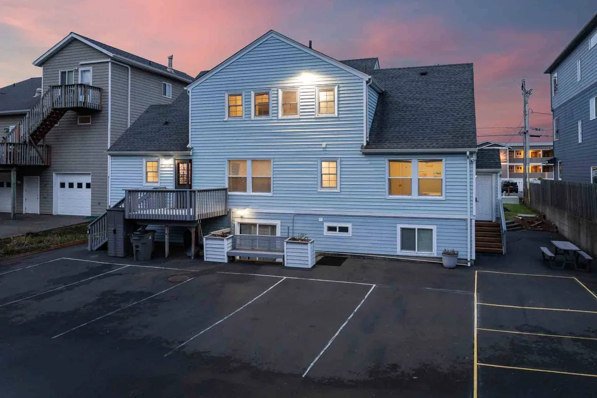 A tranquil image showing the exterior of the house, warmly lit windows, and a cozy deck area. The setting sun casts a soft glow, suggesting serene evenings spent outdoors or with loved ones. The deck is visible as a gathering place, and the exterior layout hints at secure entryways.